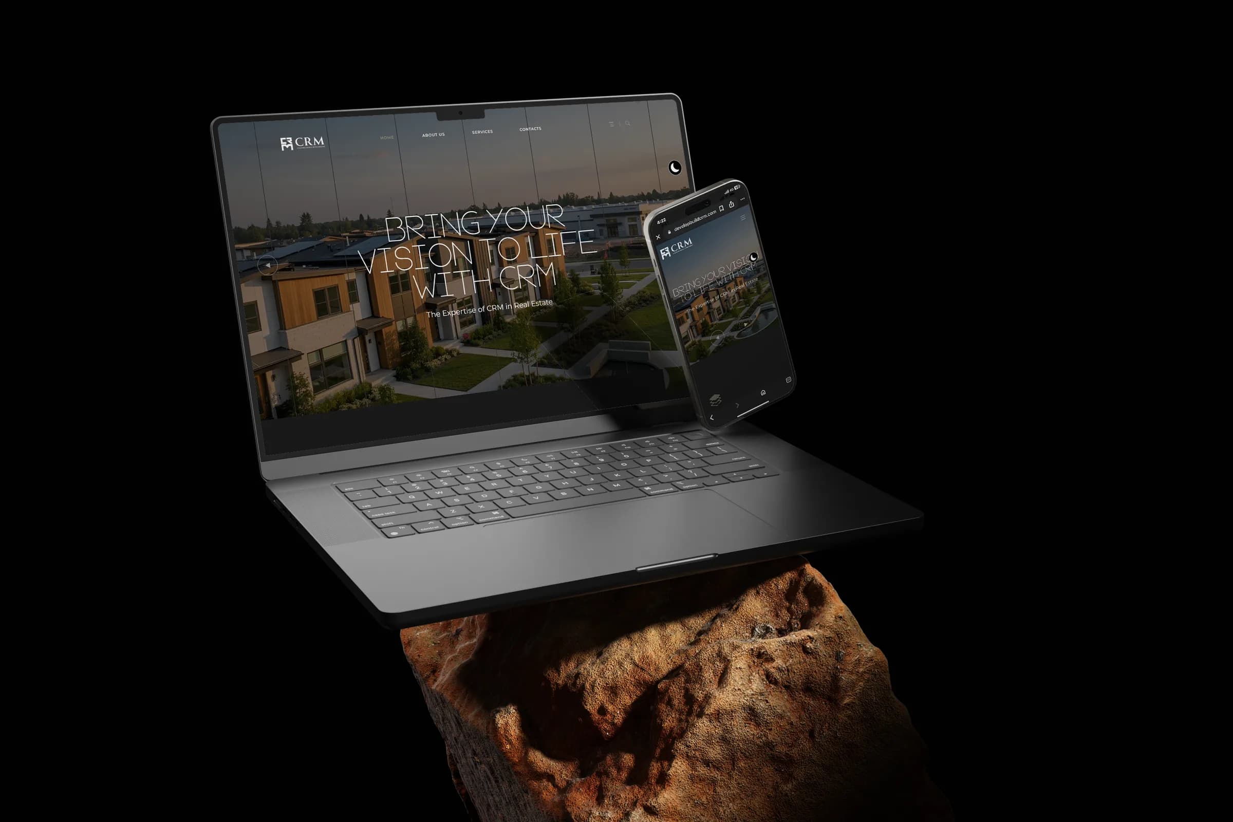 CRM Construction and Development site on a laptop and phone above glowing rock, black scene